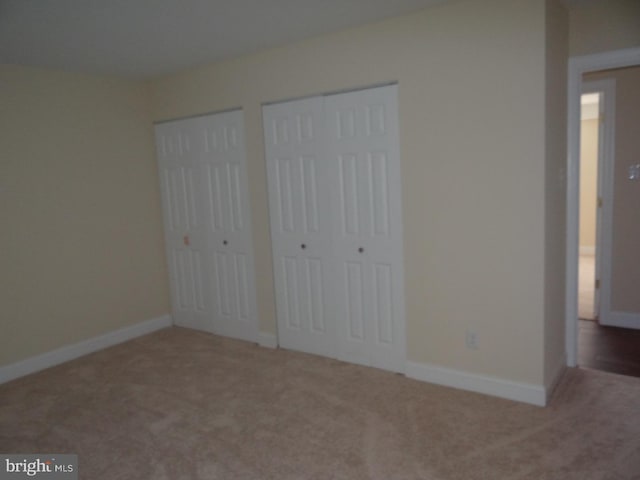 unfurnished bedroom with carpet floors and two closets