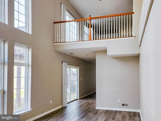 interior space featuring a wealth of natural light, a towering ceiling, and hardwood / wood-style flooring