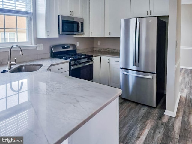 kitchen featuring dark wood-type flooring, sink, light stone counters, white cabinetry, and stainless steel appliances