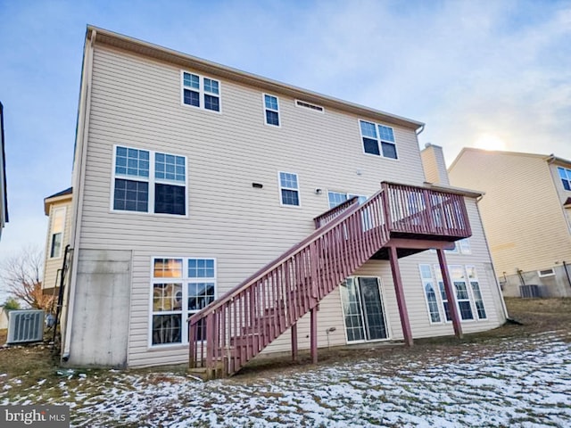 snow covered back of property featuring central AC