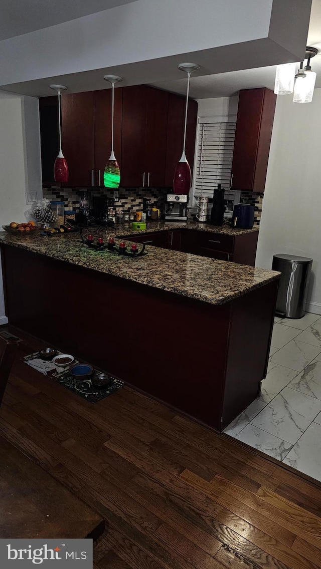 kitchen with kitchen peninsula, dark stone countertops, and pendant lighting