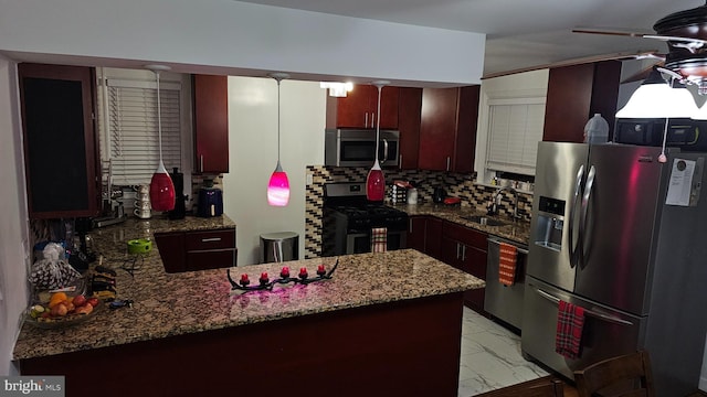 kitchen featuring sink, backsplash, kitchen peninsula, decorative light fixtures, and appliances with stainless steel finishes