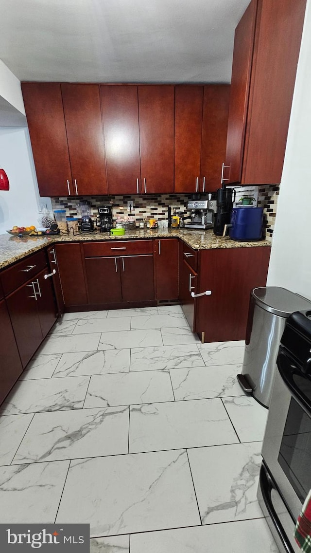 kitchen with backsplash, light stone counters, and black range