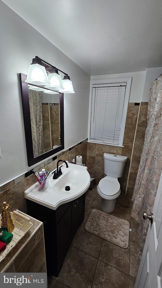 bathroom featuring vanity, toilet, and tile walls