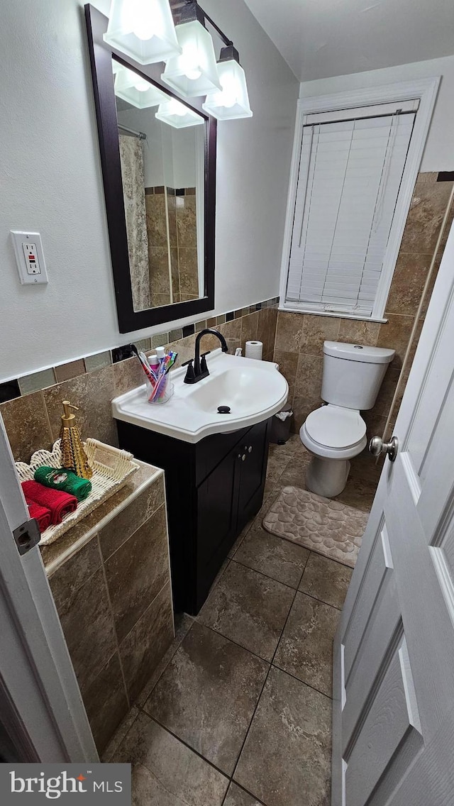 bathroom featuring vanity, toilet, and tile walls