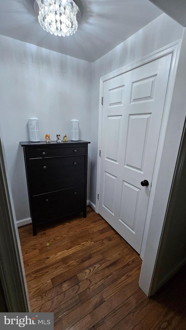 corridor with dark hardwood / wood-style floors and an inviting chandelier