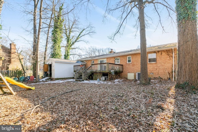 back of property with a playground, a wooden deck, and a shed