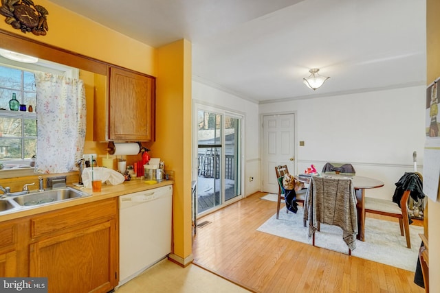 kitchen with crown molding, sink, white dishwasher, and light hardwood / wood-style floors