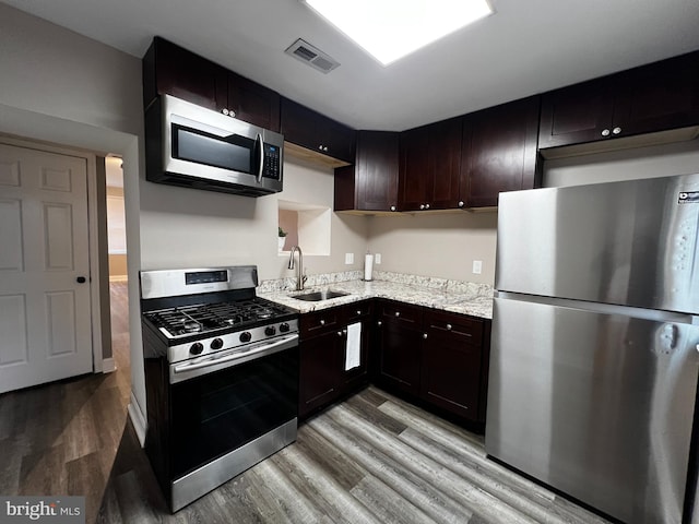 kitchen featuring dark brown cabinetry, sink, light wood-type flooring, and appliances with stainless steel finishes