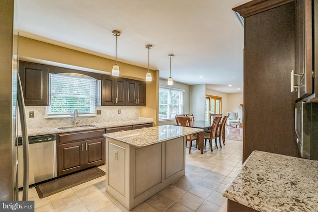 kitchen with sink, tasteful backsplash, stainless steel dishwasher, decorative light fixtures, and a kitchen island