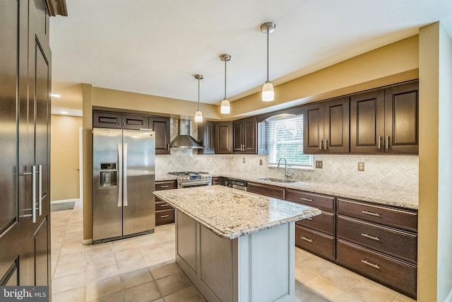 kitchen featuring sink, wall chimney exhaust hood, pendant lighting, a kitchen island, and appliances with stainless steel finishes