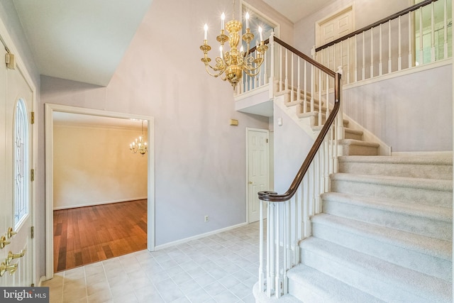 staircase with plenty of natural light, wood-type flooring, a towering ceiling, and a chandelier