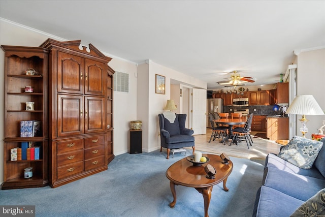 living room with light colored carpet, ceiling fan, ornamental molding, and sink