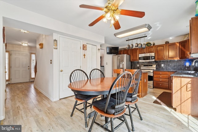 dining room featuring ceiling fan, light wood-type flooring, and sink