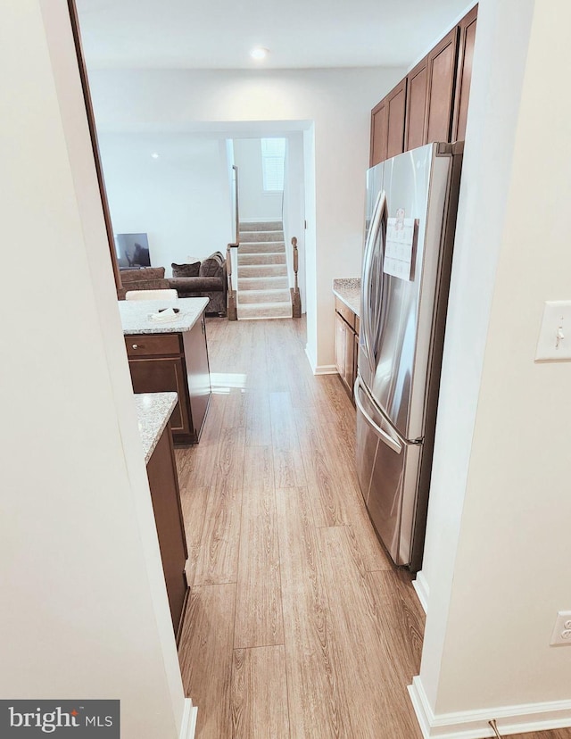 kitchen featuring light stone countertops, stainless steel fridge, and light wood-type flooring