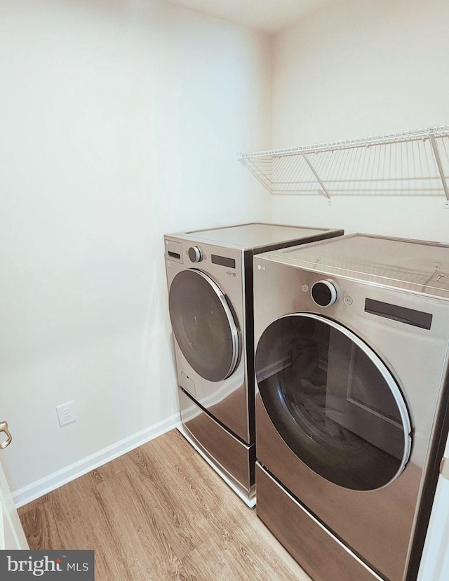 laundry area with washer and dryer and light wood-type flooring