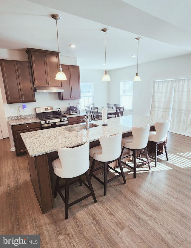 kitchen with a breakfast bar, hardwood / wood-style floors, sink, and stainless steel range with gas stovetop