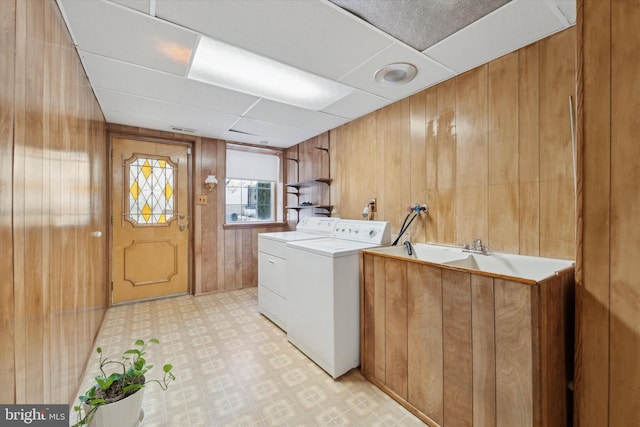 washroom featuring wood walls, cabinets, and independent washer and dryer