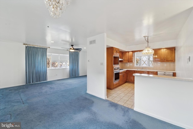 kitchen with pendant lighting, plenty of natural light, light colored carpet, and dishwasher