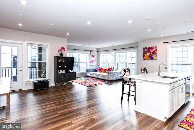 kitchen featuring a kitchen island with sink, sink, white cabinets, and dark wood-type flooring