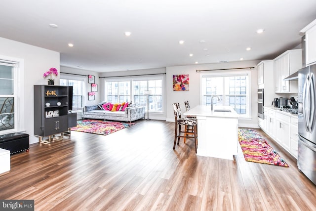 interior space featuring a kitchen bar, white cabinetry, a kitchen island with sink, and sink