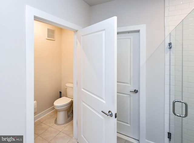 bathroom featuring tile patterned floors, toilet, and an enclosed shower