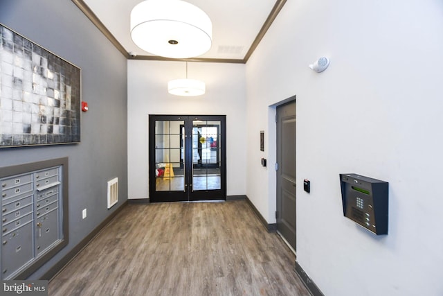 interior space featuring hardwood / wood-style flooring, a mail area, crown molding, and french doors