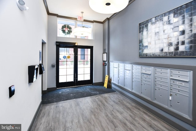 entryway with mail boxes, dark wood-type flooring, a high ceiling, and ornamental molding