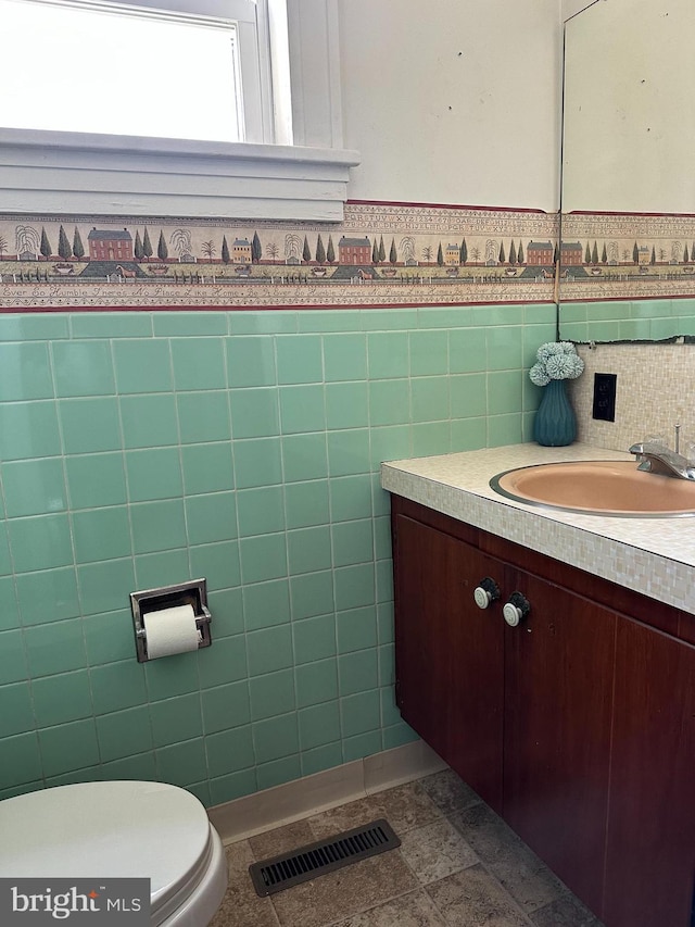 bathroom with vanity, toilet, and tile walls