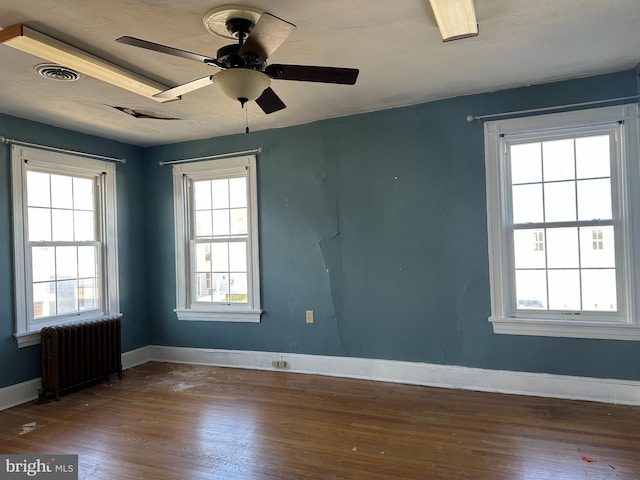 spare room featuring ceiling fan, radiator heating unit, and dark wood-type flooring