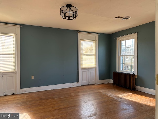 unfurnished room with radiator heating unit and wood-type flooring