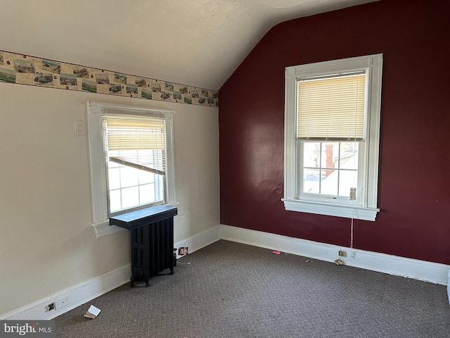 carpeted empty room with radiator heating unit and vaulted ceiling