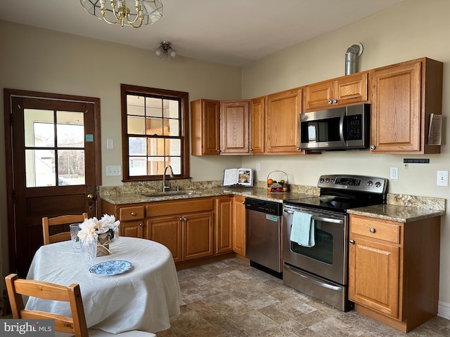 kitchen with stainless steel appliances, light stone counters, a notable chandelier, and sink