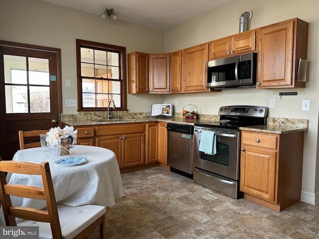 kitchen with light stone countertops, appliances with stainless steel finishes, and sink