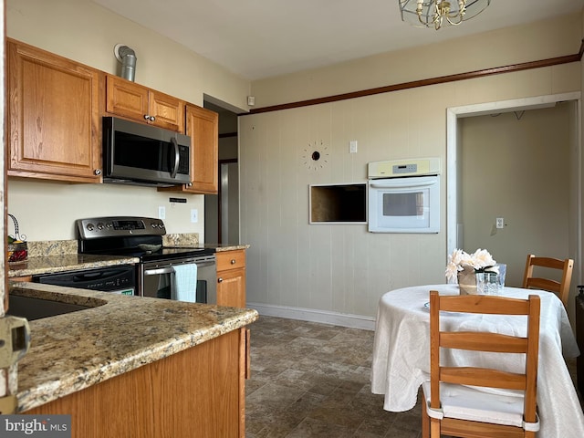 kitchen with light stone countertops, stainless steel appliances, and an inviting chandelier