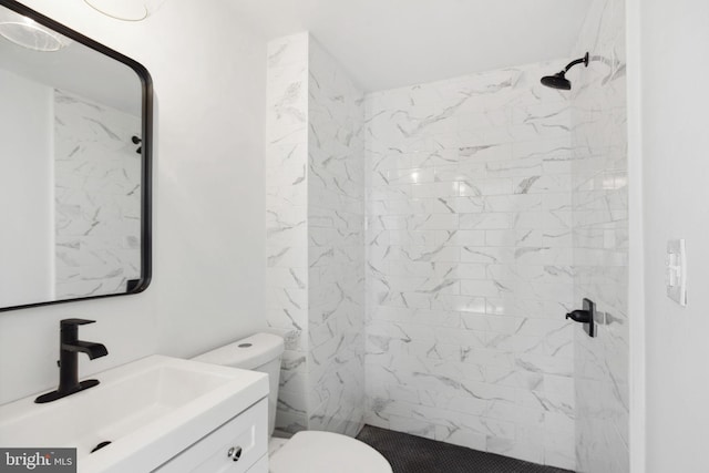 bathroom featuring a tile shower, vanity, and toilet