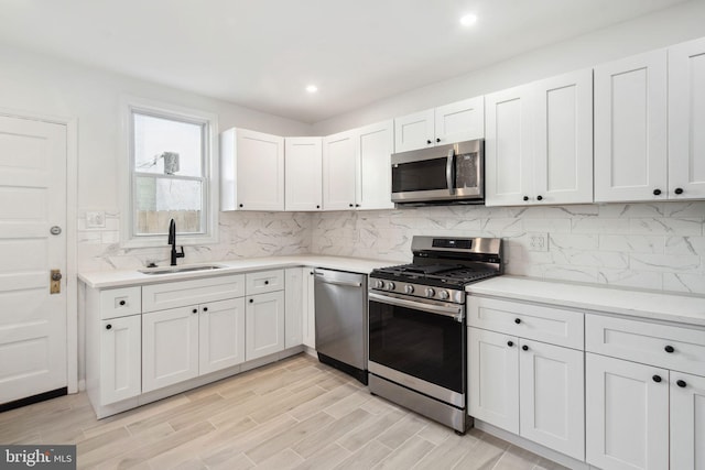 kitchen featuring stainless steel appliances, white cabinetry, tasteful backsplash, and sink