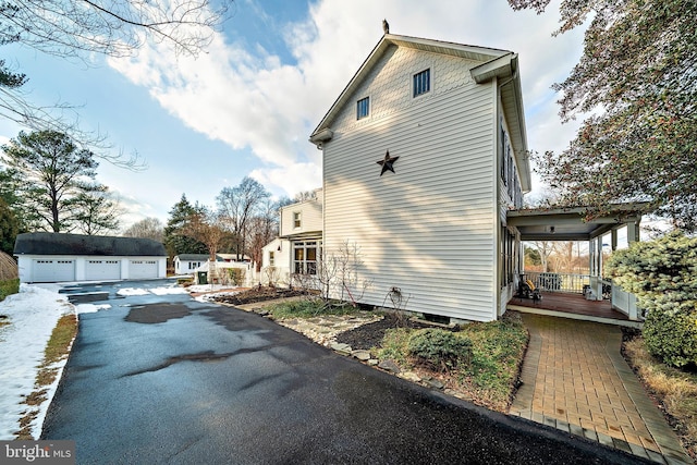 view of side of home featuring a garage, covered porch, and an outdoor structure