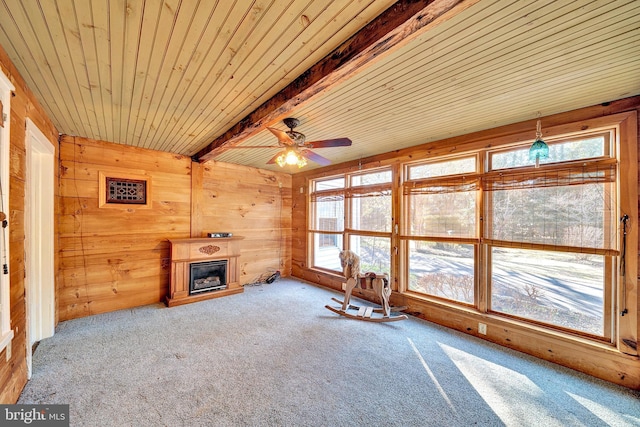 unfurnished living room featuring beam ceiling, a glass covered fireplace, wood walls, and wood ceiling