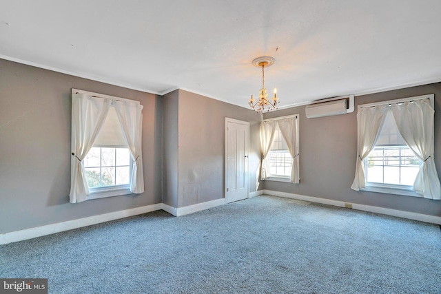 spare room featuring a wall mounted AC, carpet flooring, a wealth of natural light, and a chandelier