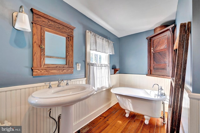 bathroom featuring wainscoting, radiator, a freestanding bath, and wood-type flooring