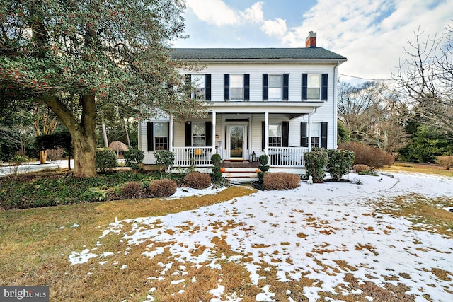 view of front facade with covered porch and a chimney