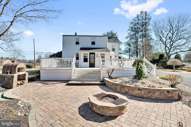 back of house with a deck, an outdoor fire pit, and a patio