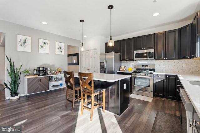 kitchen featuring stainless steel appliances, hanging light fixtures, a kitchen bar, a kitchen island, and tasteful backsplash