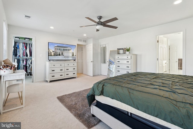 bedroom featuring light carpet, a closet, ceiling fan, and a spacious closet