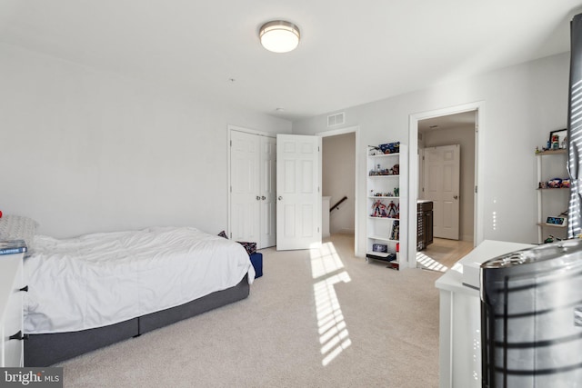 bedroom with ensuite bathroom and light carpet