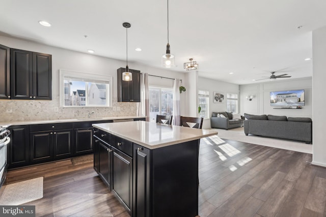 kitchen with dark wood-type flooring, a center island, decorative light fixtures, backsplash, and ceiling fan