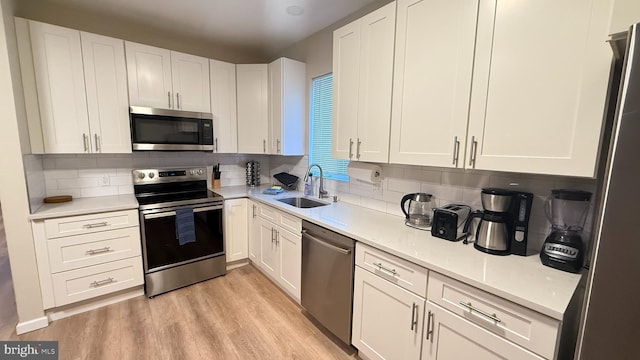 kitchen with white cabinets, decorative backsplash, stainless steel appliances, and sink