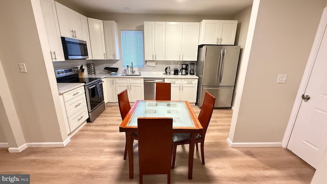 kitchen featuring white cabinets, sink, light wood-type flooring, and stainless steel appliances