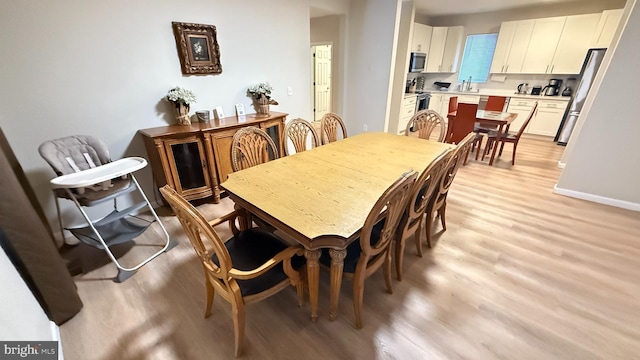 dining space featuring sink and light wood-type flooring